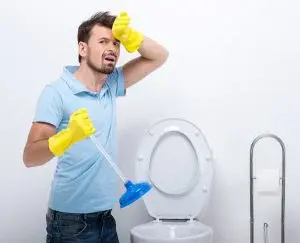 Man using a plunger on toilet