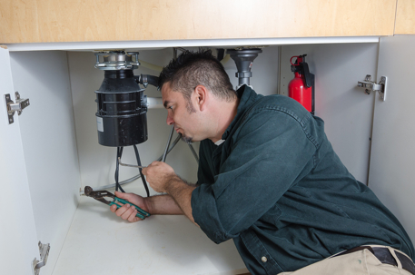 Man fixing a pipe under the sink